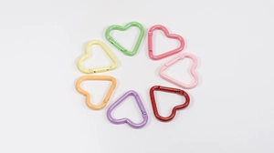 Vista de 7 mosquetones de corazón en colores macaron con cierre de resorte sobre fondo blanco