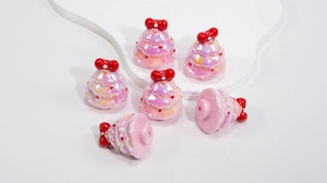 Detail of pink pearlescent Christmas tree resin bead with red bow for DIY jewelry making