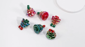 Macro detail of six metallic resin Christmas tree charms for DIY jewelry making