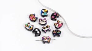 Macro detail of hand-painted cat shaped acrylic beads for DIY jewelry and crafts