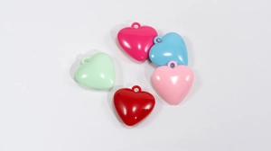 Dettaglio di cinque ciondoli a cuore in acrilico colorato rosso, rosa, blu e verde per fai-da-te