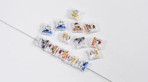 Macro shot of pillow-shaped acrylic beads with cartoon puppy motifs and central drill holes