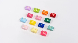 Macro shot of 14 colorful square acrylic candy beads with sun swirl patterns for DIY