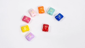 Close-up of colorful acrylic candy beads with sun motif and letter G for DIY crafts