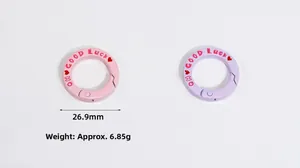 Detail of round spring snap rings in pink and purple with GOOD Luck engraving and red heart