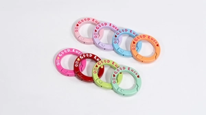 Detail van kleurrijke ronde springring sleutelhangers met QH GOOD LUCK gravure en hartjes