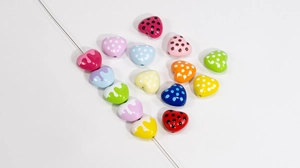 Macro shot of colorful acrylic heart beads with white dots and center hole for DIY jewelry