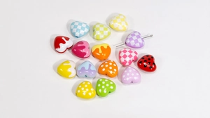 Macro shot of colorful acrylic heart beads with checkerboard and polka dot patterns for DIY