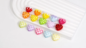 Macro shot of colorful acrylic heart beads with polka dots and checkered patterns for DIY