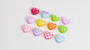 Macro detail of acrylic heart beads with checkerboard and polka dot patterns for DIY jewelry