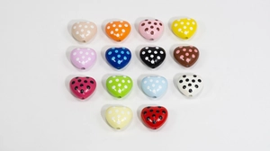 Macro shot of 14 colorful heart shaped acrylic beads with vibrant polka dot patterns for DIY