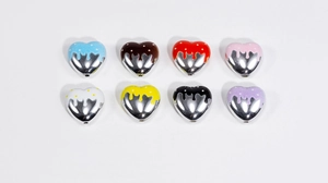 Détail macro de huit perles cœur émaillées colorées avec base argentée pour bijoux DIY
