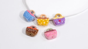 Close-up of acrylic handbag-shaped beads with colorful patterns for DIY accessories