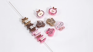 Macro detail of leopard print acrylic beads in apple and bow shapes for DIY jewelry making