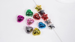Nahaufnahme bunter Metall-Stern- und Herz-Acrylperlen mit LOVE-Prägung für DIY-Projekte