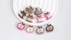 Detailed close-up of acrylic leopard print beads in apple and cherry shapes for DIY crafts
