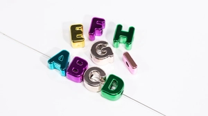 Macro view of metallic acrylic alphabet beads A-I showing hollow holes and vibrant plating