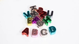 Macro detail of colorful metallic acrylic alphabet beads with holes for DIY jewelry making
