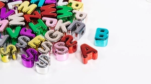 Macro view of colorful metallic acrylic alphabet beads with large holes for DIY jewelry