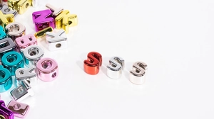 Macro shot of colorful metallic letter beads with side holes for DIY jewelry making