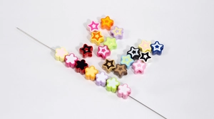 Macro detail of assorted acrylic flower and star beads with pre-drilled holes for DIY