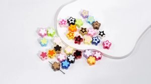 Close-up of colorful acrylic flower and star beads with needle for DIY jewelry making