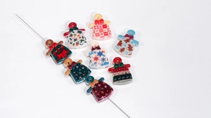 Macro detail of Christmas acrylic beads in bell and clothing shapes for DIY jewelry making