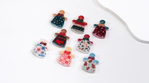 Flat lay of colorful acrylic Christmas dress pendants with festive patterns and bows