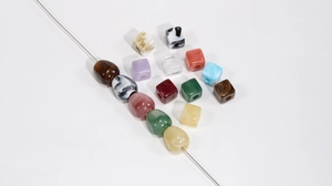 Macro shot of assorted colorful marble-patterned square and oval beads for DIY crafts