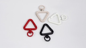 Macro view showing triangular alloy keychains in red, beige, white and black matte finishes