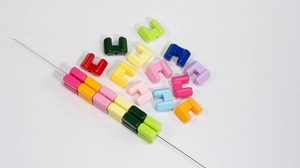 Macro detail of high-gloss acrylic U-shaped beads in vibrant colors for DIY jewelry making