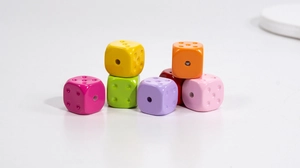 Macro shot of colorful dice-shaped acrylic beads with central holes for DIY jewelry