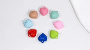 Close-up of eight colorful acrylic heart pendants with textured patterns for DIY jewelry