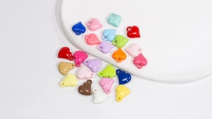 Macro shot of colorful glossy heart charms with gold loops for DIY jewelry making