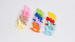 Close-up of colorful acrylic rocking horse charms with hanging loops for DIY crafts