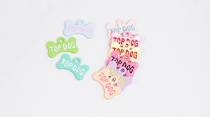 Macro-opname van gekleurde botvormige legering hangers met TOP DOG gravure voor DIY