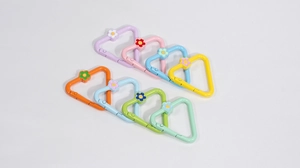 Close-up of colorful triangle spring hooks with small flower charms for DIY crafts