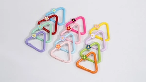 Macro view of colorful triangle spring clasps with small flower charms for DIY crafts