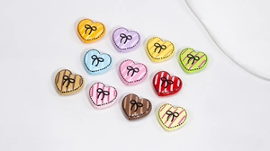 Dettaglio di ciondoli a cuore colorati con fiocchi neri per creazioni di gioielli DIY
