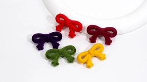 Détail de cinq breloques nœuds floqués colorés pour la création de bijoux DIY