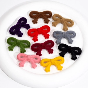 Pendentifs nœuds floqués multicolores en dix teintes sur une assiette blanche