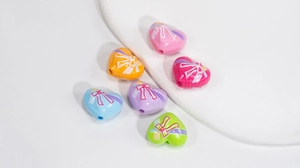 Nahaufnahme von herzförmigen Acrylperlen mit Schleifendruck für DIY-Schmuck