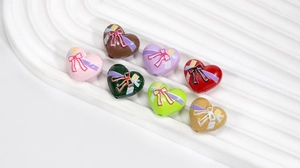 Bunte Acrylperlen in Herzform mit Schleifen für DIY-Schmuck auf weißem Sockel