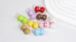 Dettaglio di perline colorate a fiocco in acrilico con pois bianchi per gioielli fai da te
