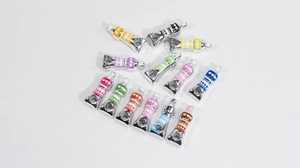 Macro shot of silver-plated acrylic paint tube charms with colorful enamel and Love engraving