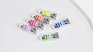 Detailed view of colorful enamel paint tube charms with love text for DIY jewelry making