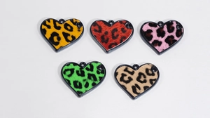 Dettaglio macro di ciondoli a cuore in acrilico con stampa leopardata in cinque colori