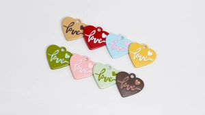 Macro detail of eight colorful enamel heart pendants with cursive love engraving