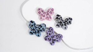 Detailed view of acrylic leopard print butterfly beads in pink purple blue and white colors