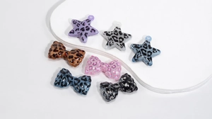Detail view of acrylic leopard print star and bow charms for jewelry and keychains